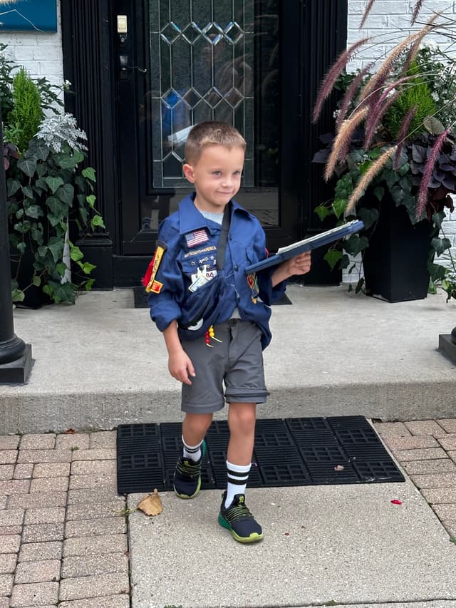 A Pack 5 Scout selling popcorn at a storefront shift